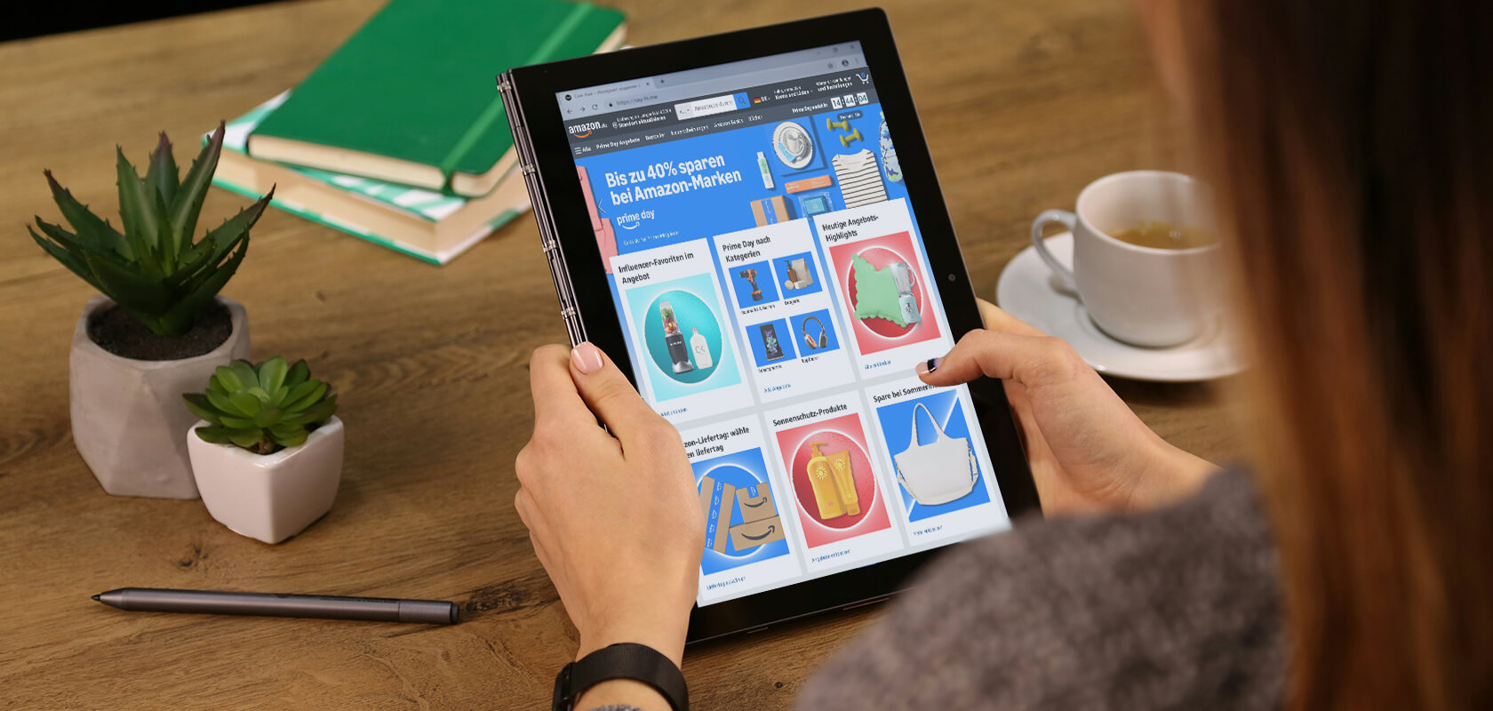 Eine Person hält ein Tablet, auf dem ein Online-Marktplatz angezeigt wird. In der Nähe liegen ein Stift, Bücher, eine Sukkulente und eine Tasse Kaffee auf einem Holztisch.