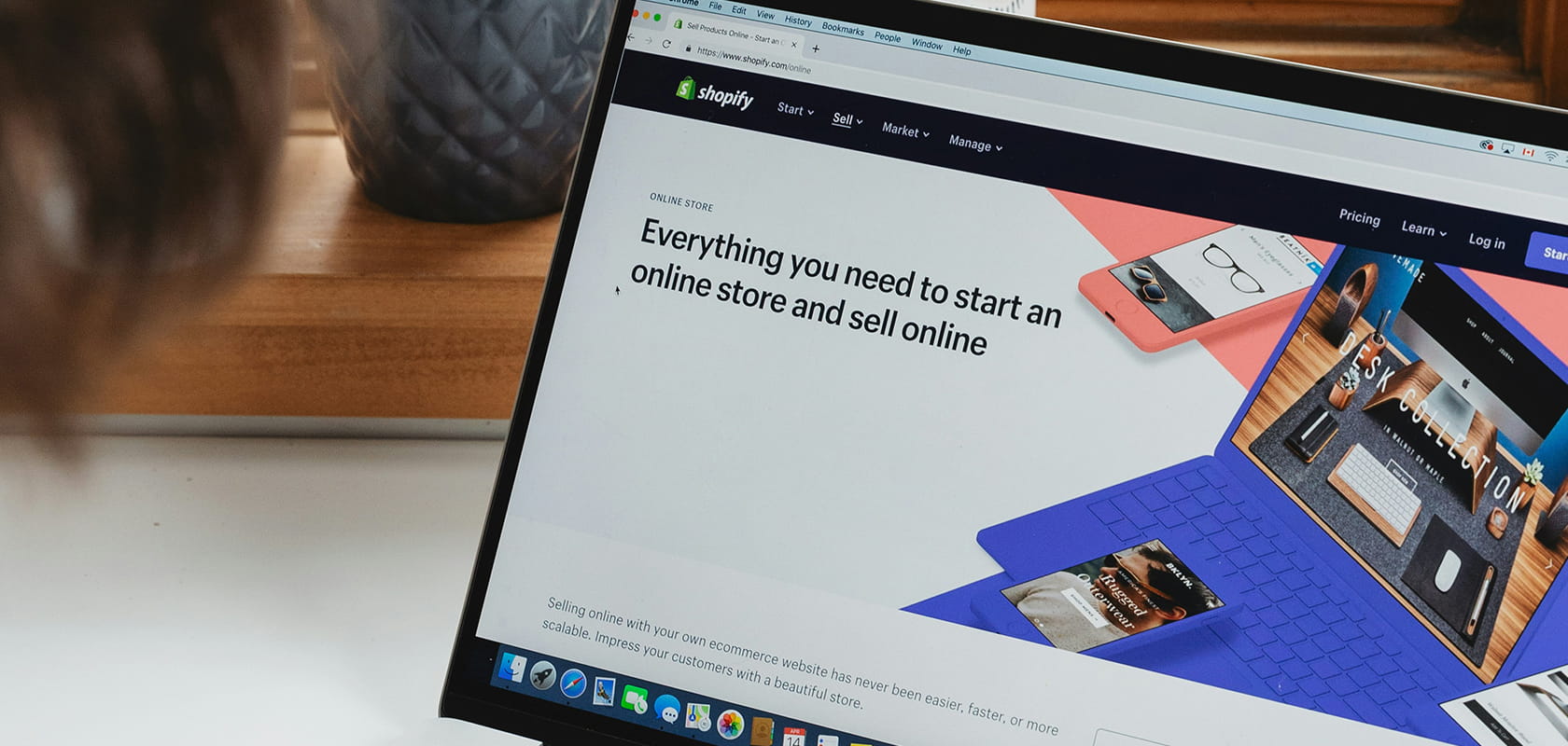 Laptop screen displaying Shopify's website, featuring text "Everything you need to start an online store and sell online" next to bright visuals.