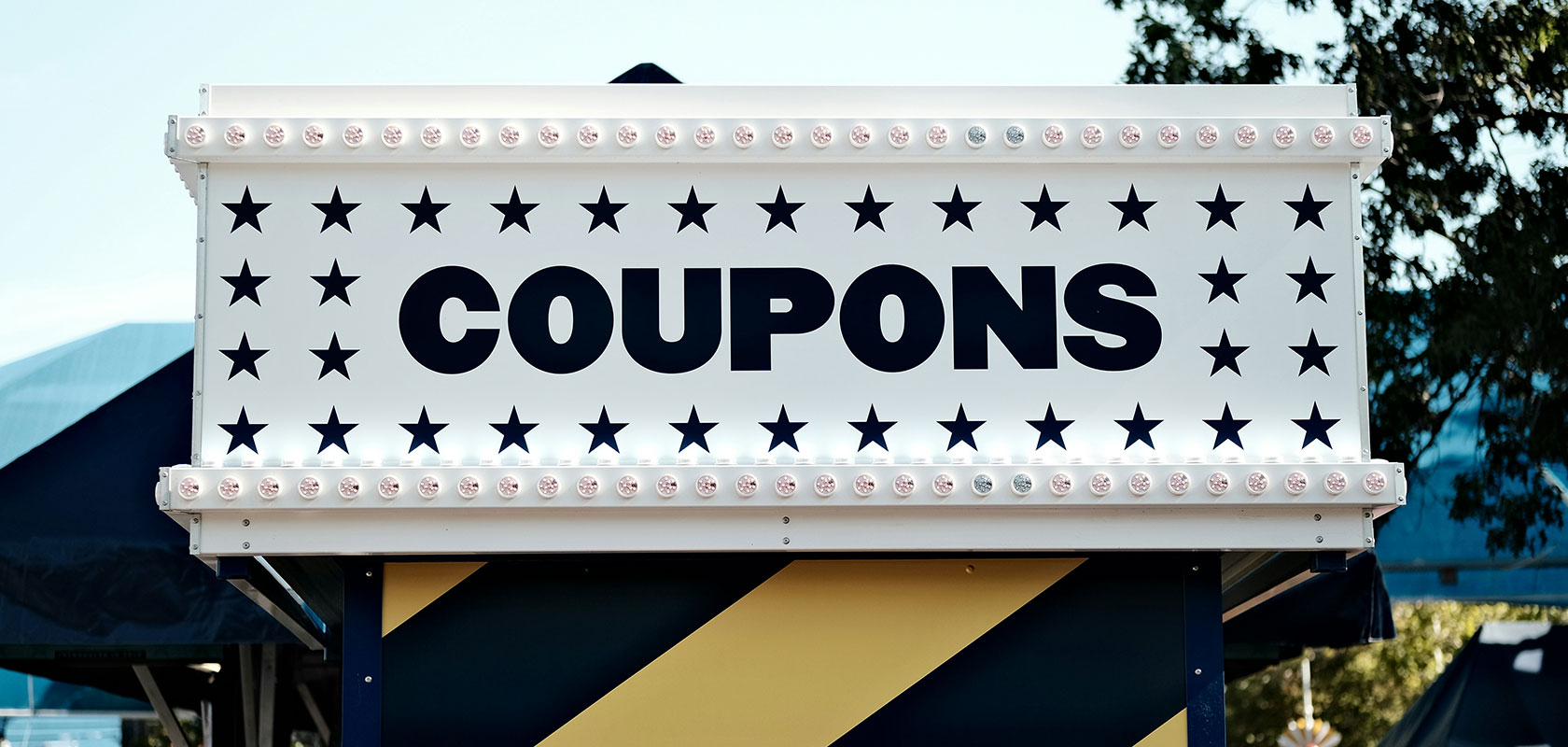 Leuchtsschild im Jahrmarkt-Stil mit der Aufschrift „COUPONS“ und Sternen-Dekoration.