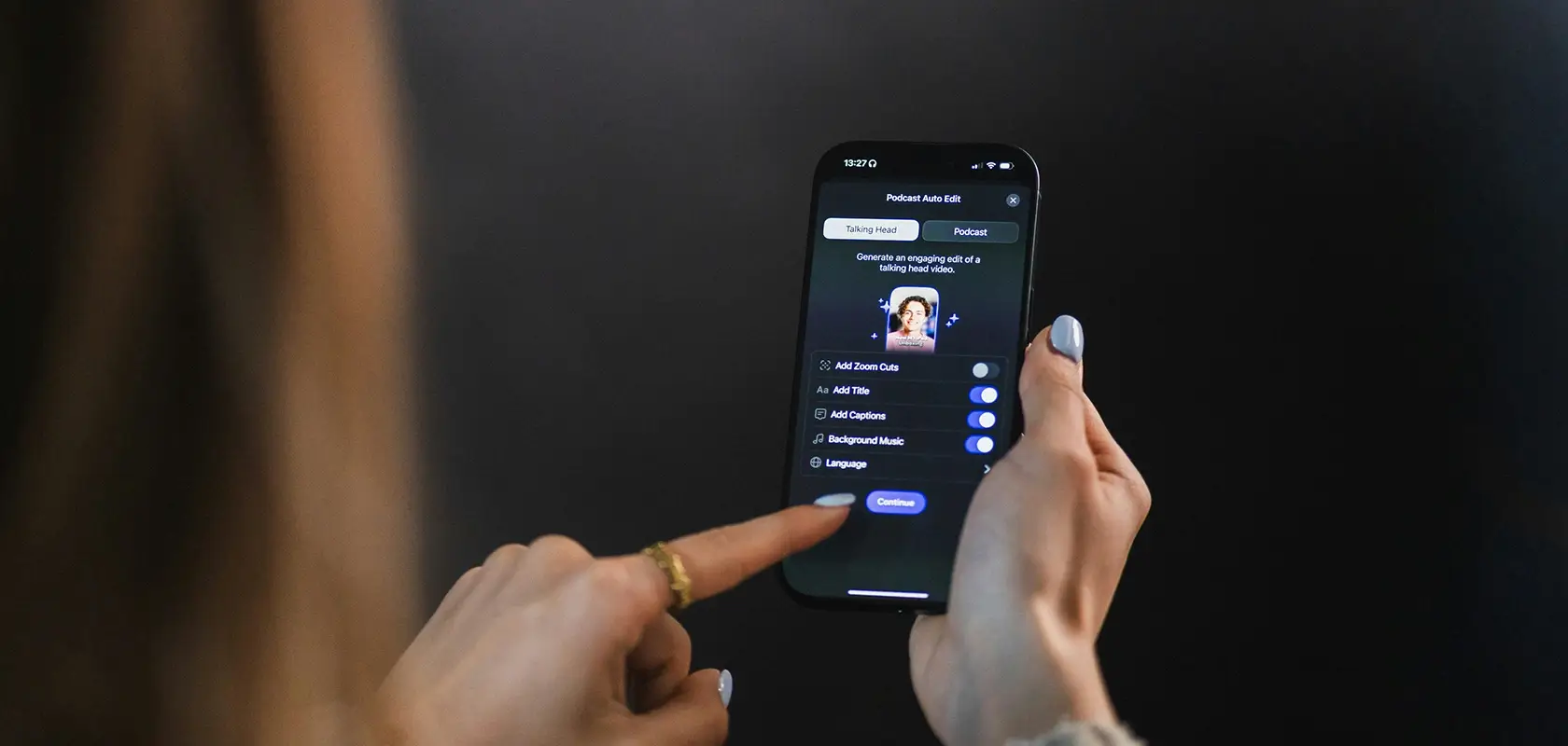 Person using a smartphone with a black screen interface, adjusting photo settings. Finger poised over a button against a dark background.