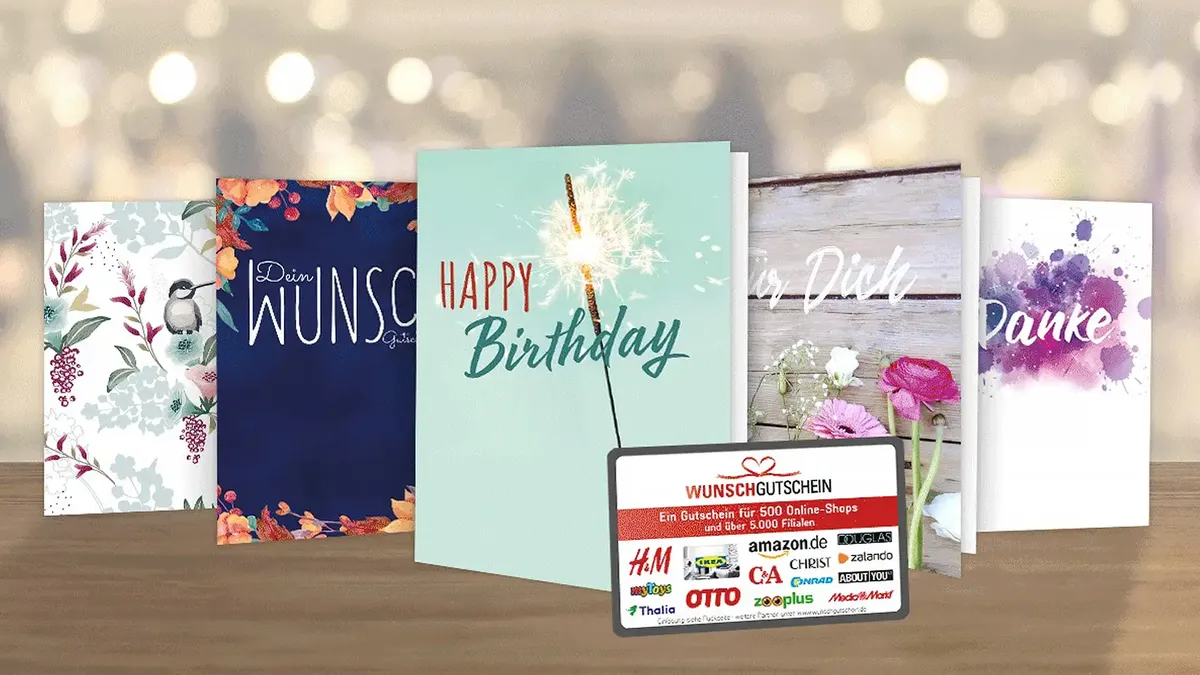 Eine Vielzahl von Grußkarten mit Blumenmotiven und eine Geschenkkarte mit mehreren Geschäftslogos, die auf einer Holzfläche ausgestellt sind.