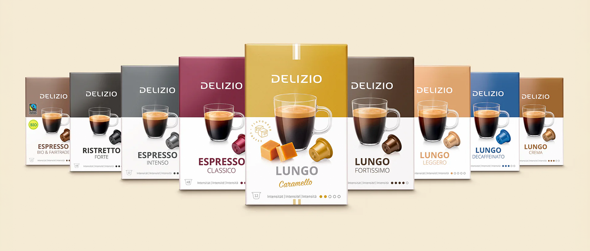 Eine Reihe von Delizio-Kaffeekapselboxen in verschiedenen Geschmacksrichtungen, jede mit einem Kaffeetassenbild, vor einem hellbeigen Hintergrund.