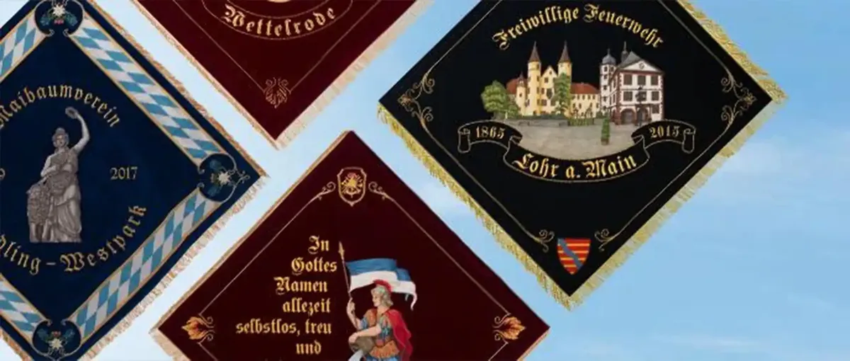 Vier dekorative Banner mit komplizierten Motiven, darunter eine Statue, ein Schloss und ein deutscher Text, diagonal auf hellem Hintergrund angeordnet.