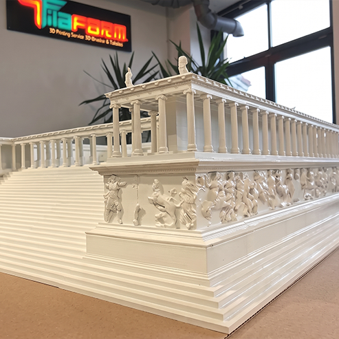 Ein im 3D-Druckverfahren hergestelltes maßstabsgetreues Modell eines antiken griechischen Tempels mit detailgetreuen Säulen und Friesen, ausgestellt in einem Büro mit einer Leuchtreklame im Hintergrund.