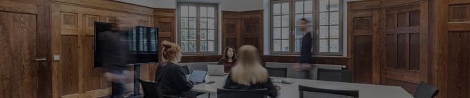 Dynamisches Meeting im Gründerzimmer, Personen in Bewegung und Diskussion am Tisch