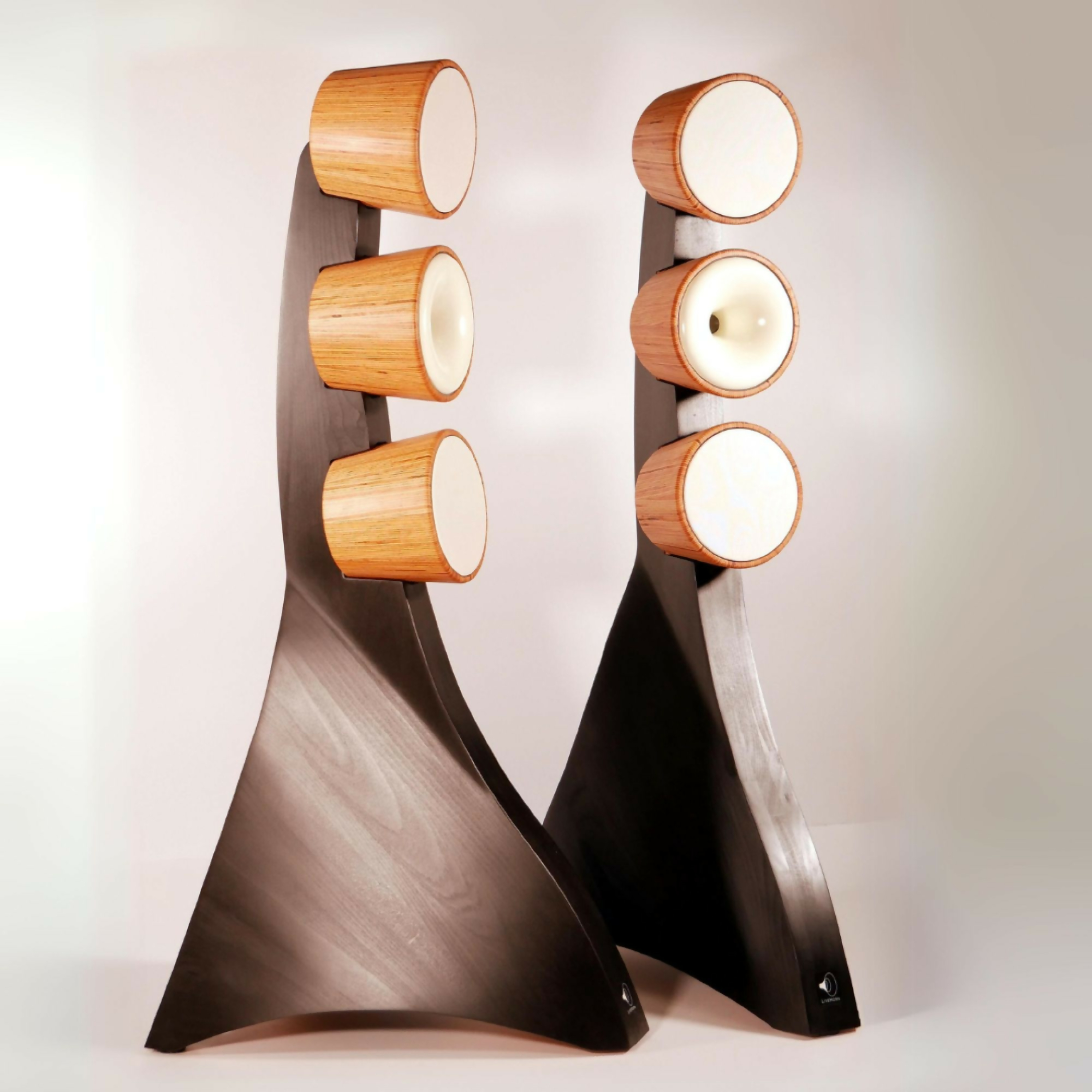 Enceintes modernes en bois avec une base noire élégante et incurvée, chacune comportant trois composants circulaires empilés verticalement.