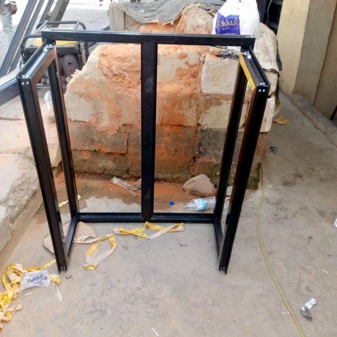 Black metal frame standing outdoors on a concrete surface, surrounded by debris and construction materials.