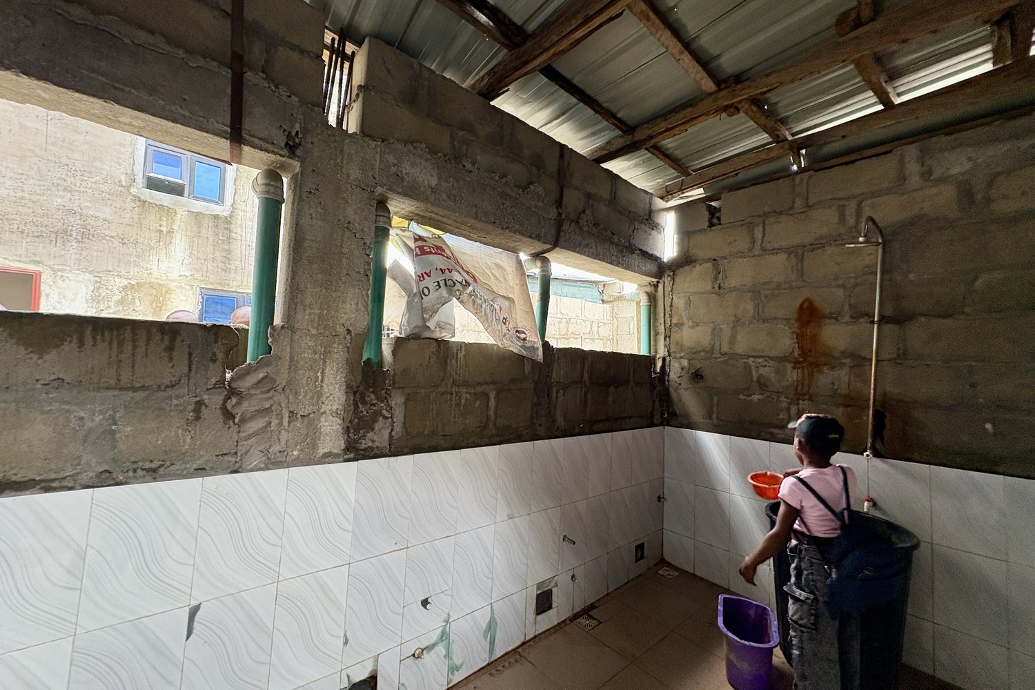 Inside the donated space, half-tiled walls and unfinished blockwork under a corrugated roof