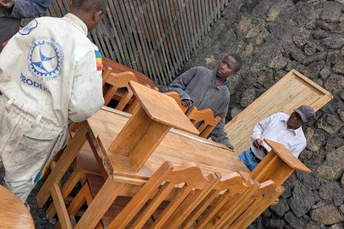 Trainees unloading wooden school desks and chairs they built during the programme.