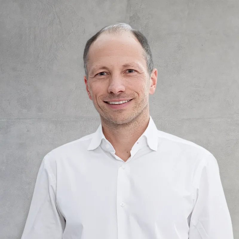 Smile Eyes Augenarzt Dr. med. Niklas Kellermann, der lächelnd in einem hellen, modernen Büroraum steht.