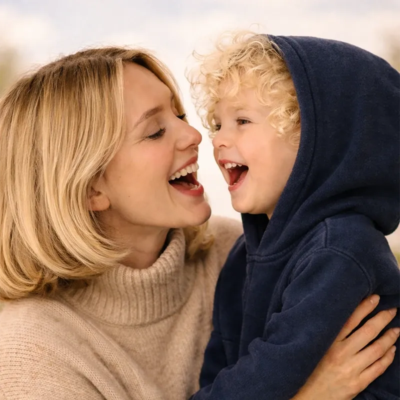 Mutter mit ihrem lachenden Kind als Symbolbild für gutes Sehen und die frühzeitige Diagnose einer Hornhautverkrümmung bei Kindern.