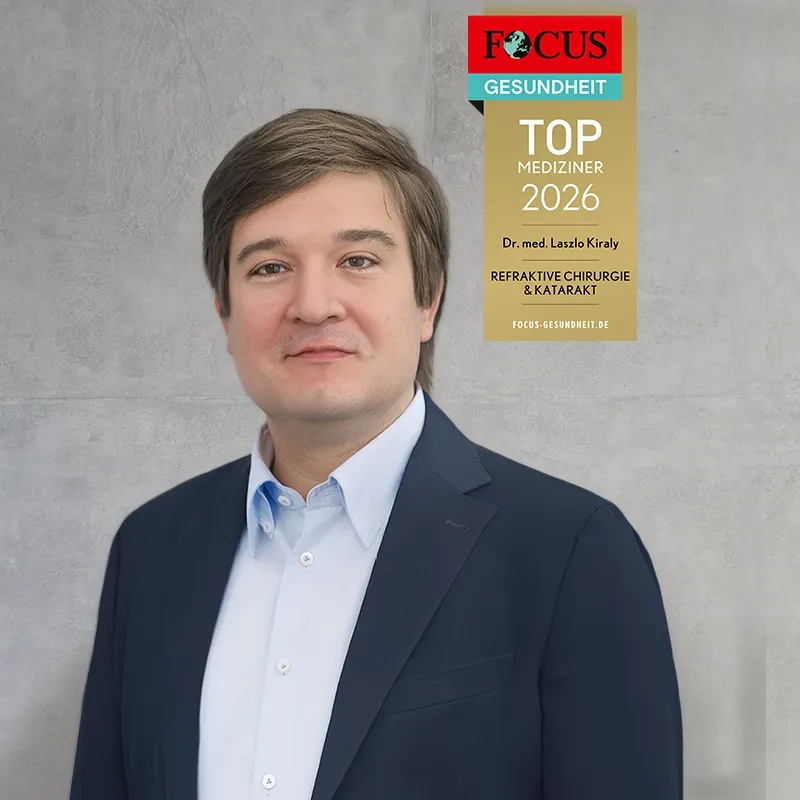 Smile Eyes Augenarzt Laszlo Kiraly lächelnd vor einem unscharfen Hintergrund. „Focus Gesundheit“ zeichnet mit einem Siegel Dr. med. Laszlo Kiraly als „Top Mediziner 2025“ aus.