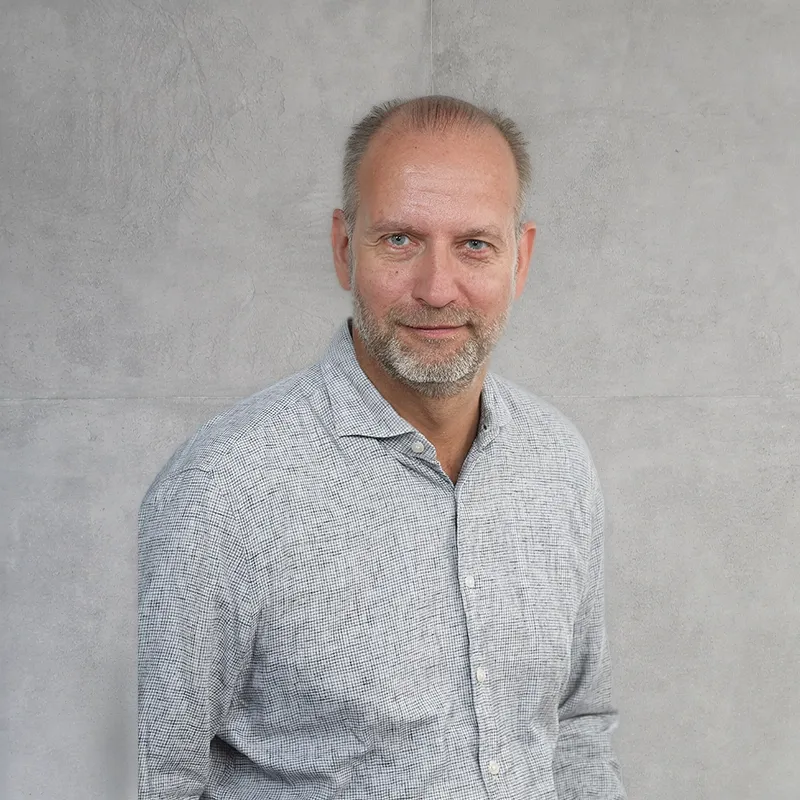 Smile Eyes Augenarztes Dr. Jörn Kuchenbecker steht lächelnd in einem hellen, modernen Büroraum.