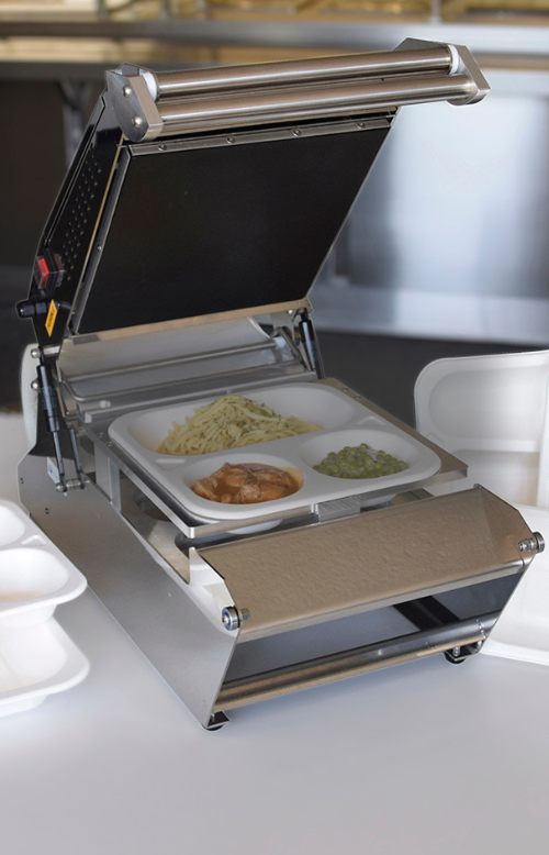 Siegelmaschine versiegelt Menüschale mit Essen darin