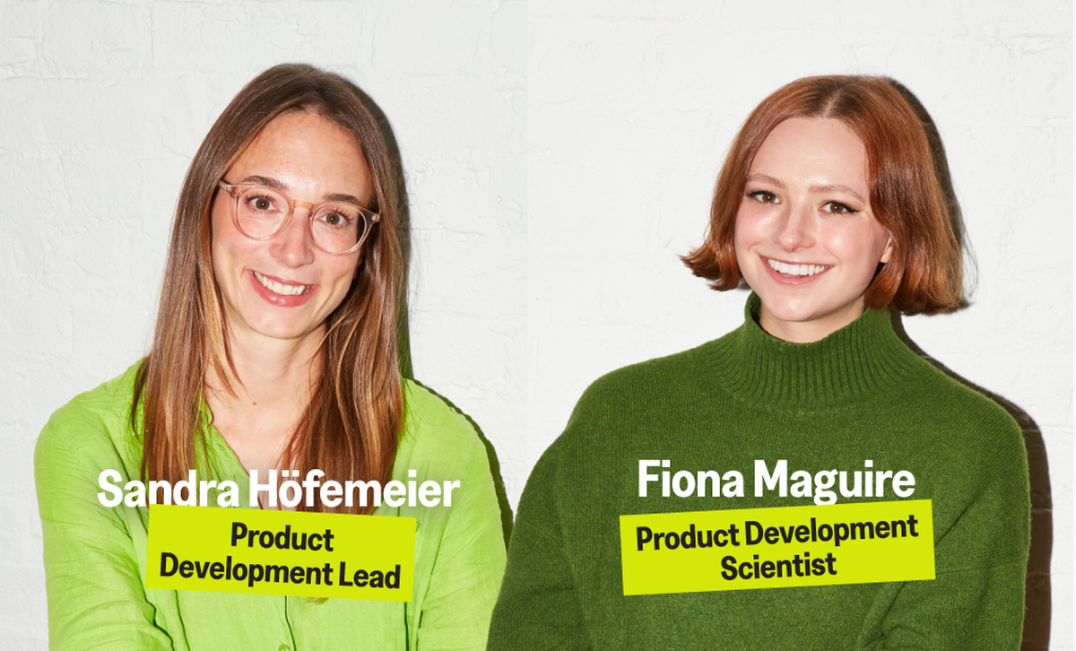 Two women smiling against a white wall; one in a lime green shirt labeled as Product Development Lead, the other in a green sweater as Product Development Scientist.