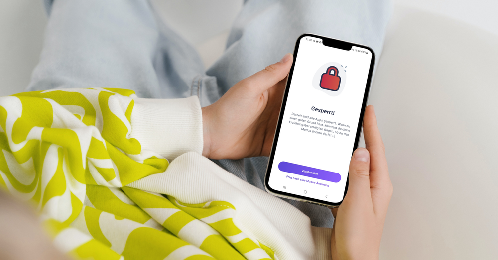 Kind hält Handy, Bildschirm zeigt Info, dass alle Apps derzeit gesperrt sind