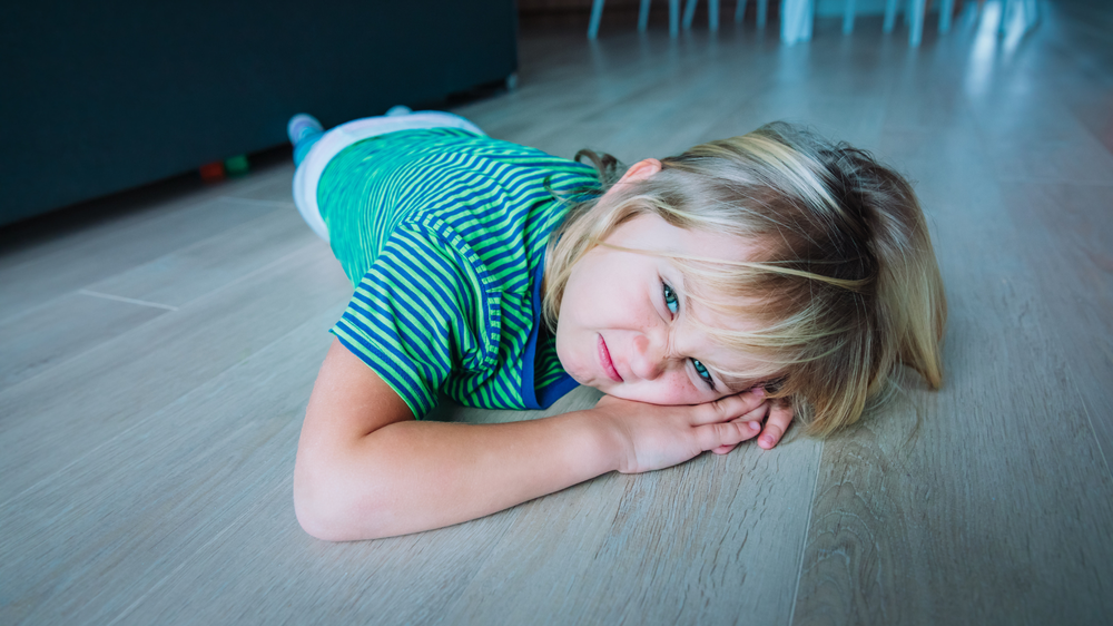 little girl is on the floor, making a frowny, angry face