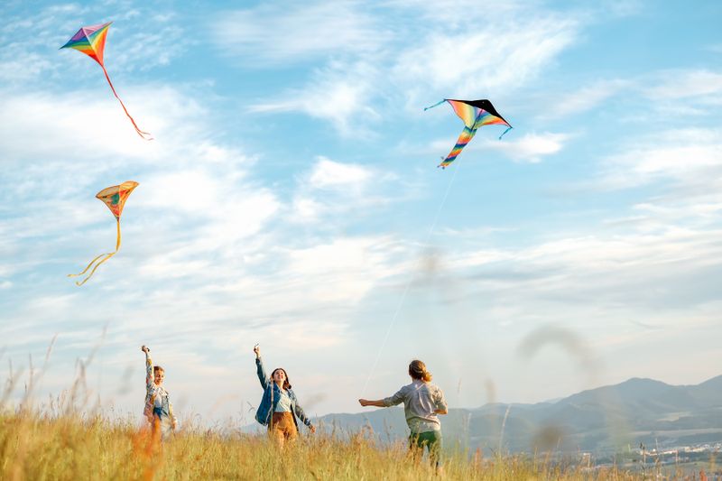 Drei Kinder lassen ihre bunten Drachen im Wind fliegen