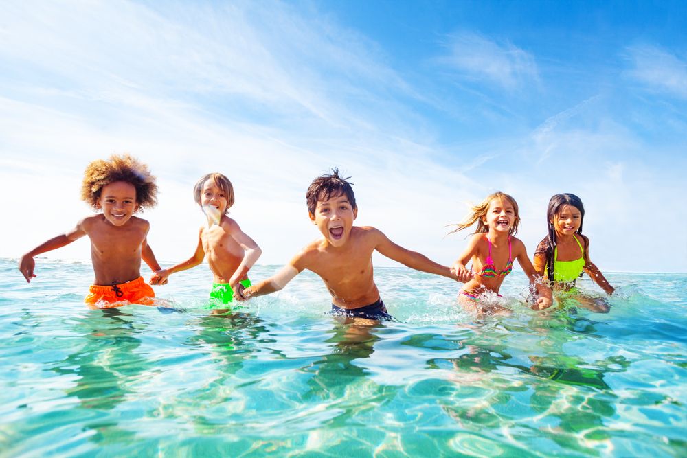 Kinder sind im Meer und laufen lachend in Richtung Kamera