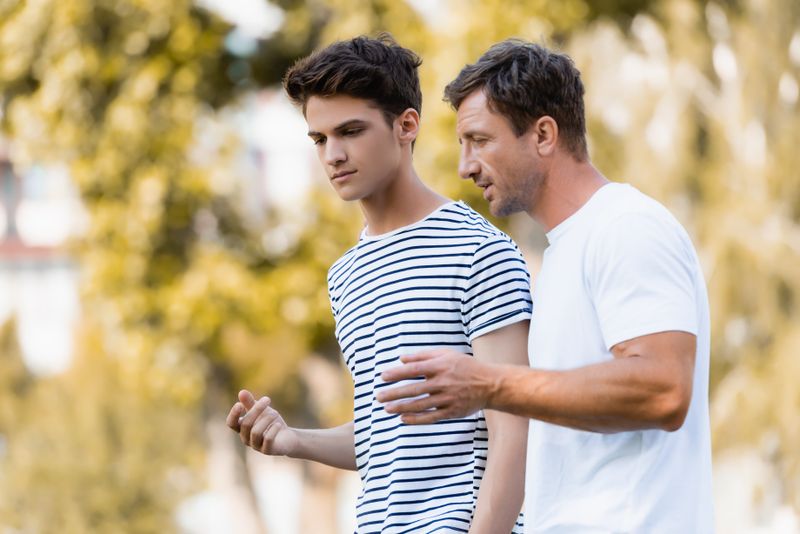 Vater erklärt jugendlichem Sohn beim Spaziergang in der Natur etwas