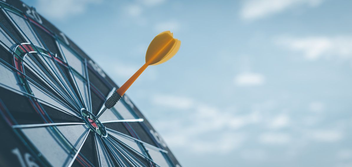 A yellow dart is striking the bullseye of a dartboard, set against a blue sky background.