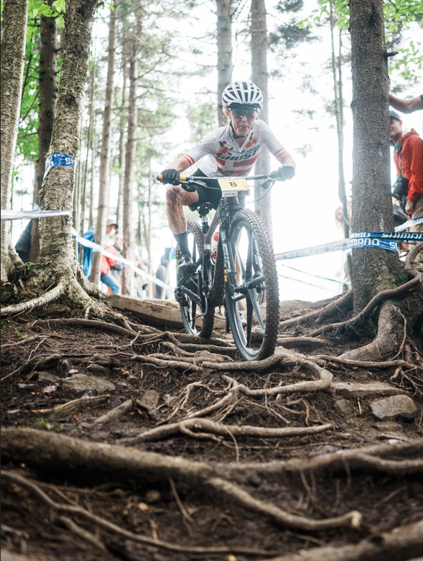 Caroline Bohé cycling downhill over tree roots in Snowshoe USA