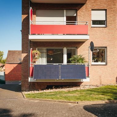 Ein Balkonkraftwerk bestehend aus zwei Solarpanelen am Balkon eines Mehrfamilienhauses.