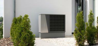 Eine modern wirkende Wärmepumpe an einer Hauswand.