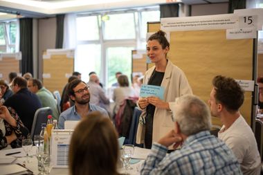 Eine Frau präsentiert eine handschriftliche Karte ihrer Kleingruppe bei einem Bürgerrat.