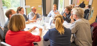 Eine Kleingruppe diskutiert, Kärtchen auf dem Tisch und an den Wänden.