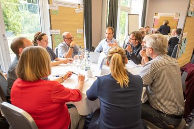 Eine Kleingruppe diskutiert, Kärtchen auf dem Tisch und an den Wänden.