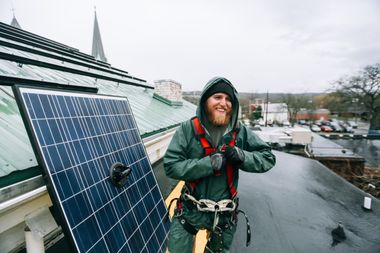 Ein Handwerker installiert ein PV Panel auf einem Dach.
