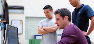 Drei Menschen schauen auf einen Computerbildschirm.