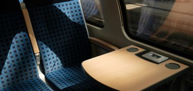 Ein leerer Vierersitz im Zug der Deutschen Bahn mit kleinem Tisch, auf den die Sonne scheint.