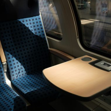 Ein leerer Vierersitz im Zug der Deutschen Bahn mit kleinem Tisch, auf den die Sonne scheint.
