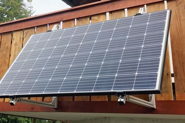 Ein Balkonkraftwerk an einer hölzernen Ballustrade.