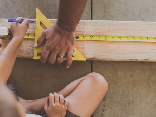 Little boy measuring wood with dad