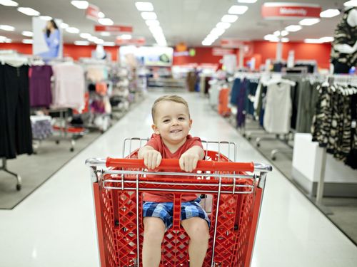 A boy sitting in a shopping cart in a fashion store
