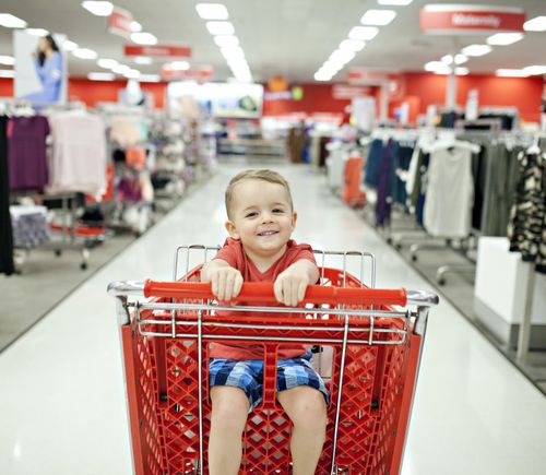 A boy sitting in a shopping cart in a fashion store