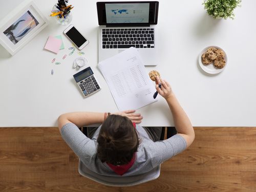 Woman at desk eating a cookie