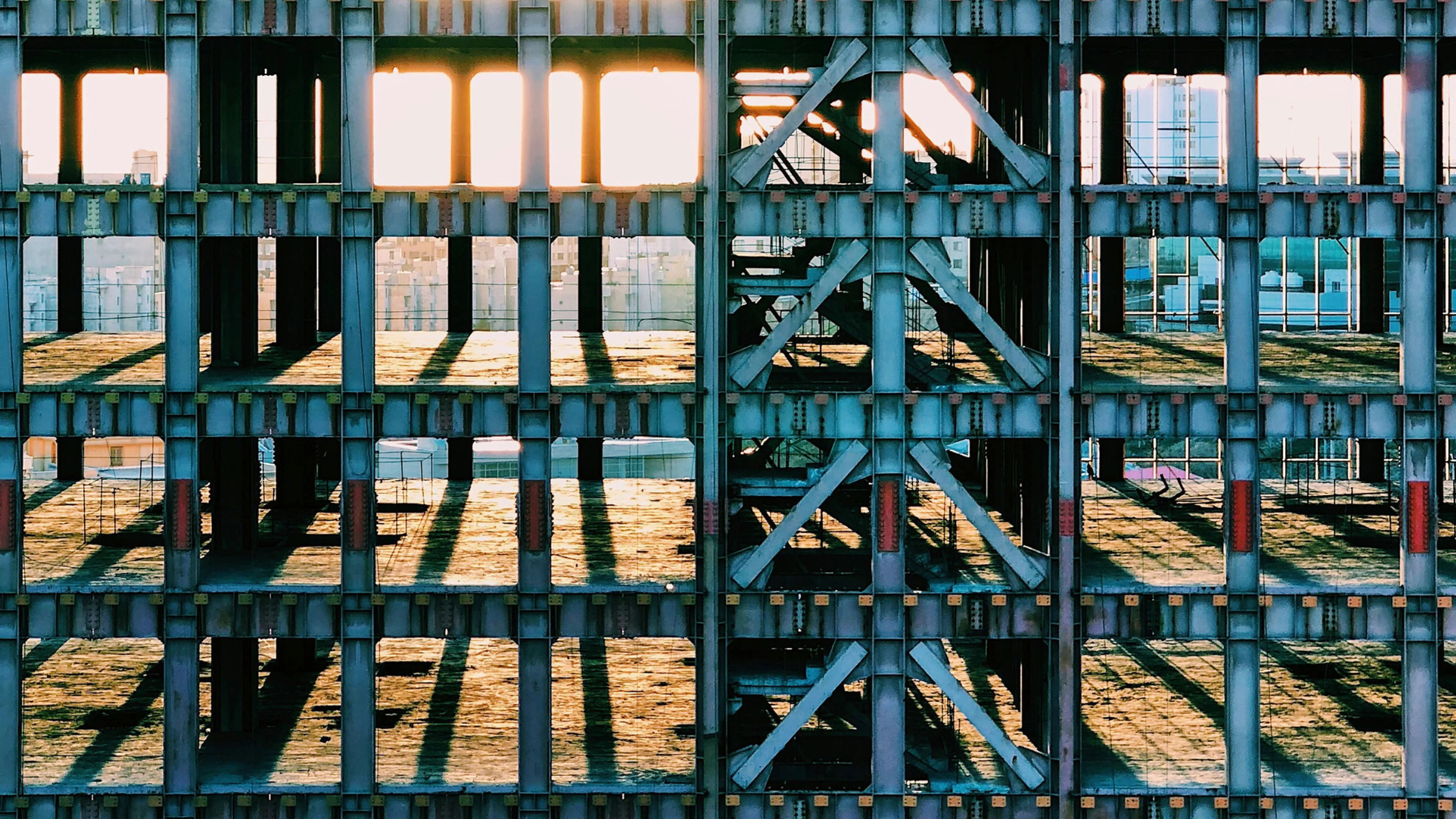 Sunlight casting shadows through the skeletal frame of a building under construction.