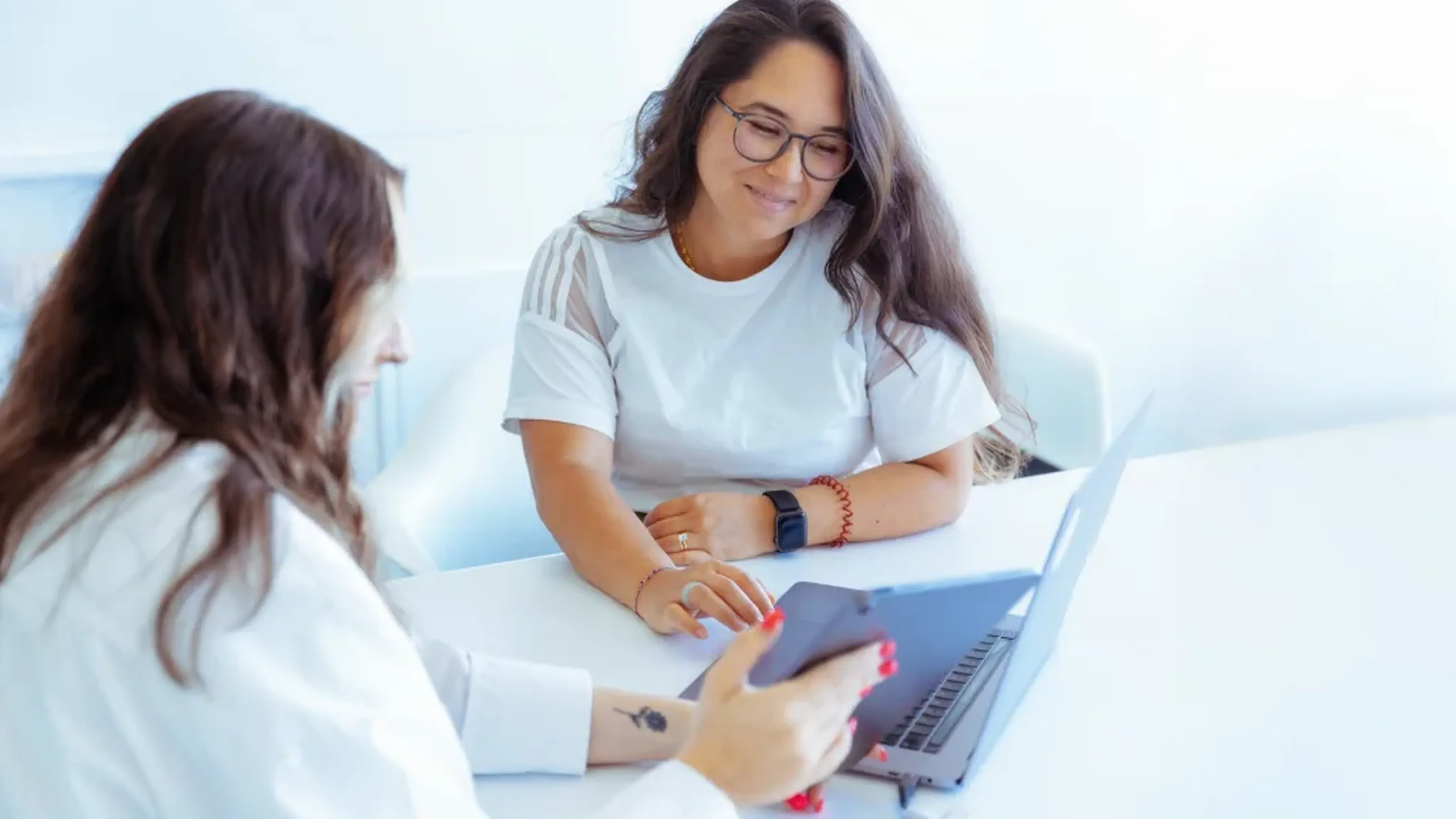 Zwei Frauen arbeiten gemeinsam mit einem Laptop und einem Tablet.