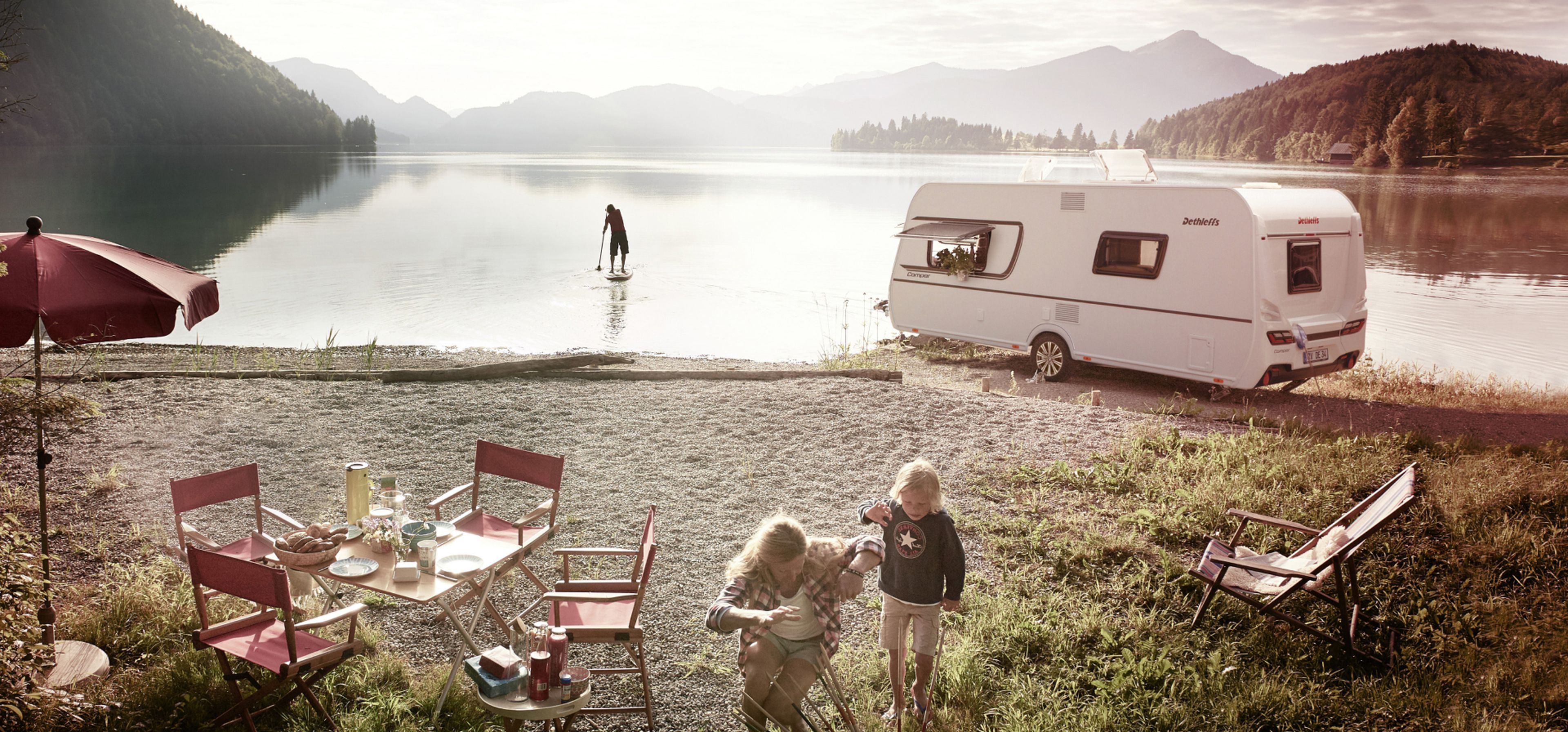 Dethleffs Wohnwagen an einem Bergsee, daneben sind Mutter und Kind.
