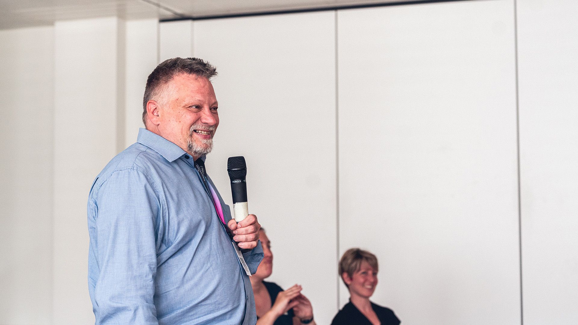 A man is giving a presentation with a microphone, smiling.
