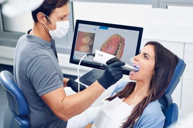 Zahnarzt setzt CEREC-System bei Patientin ein.
