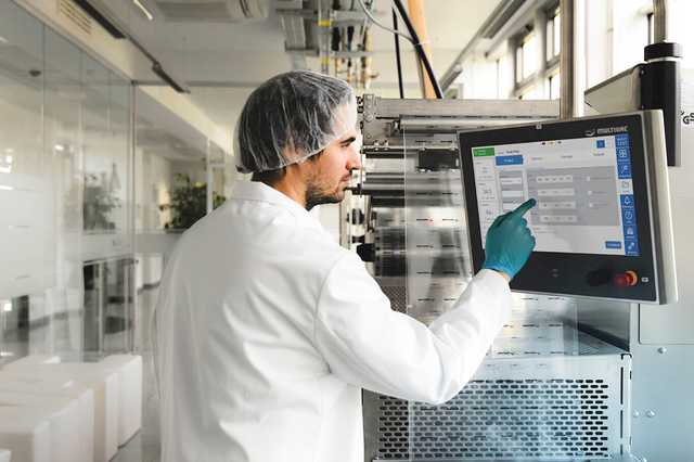 Mann im Kittel bedient HMI der Multivac Verpackungsmaschine.