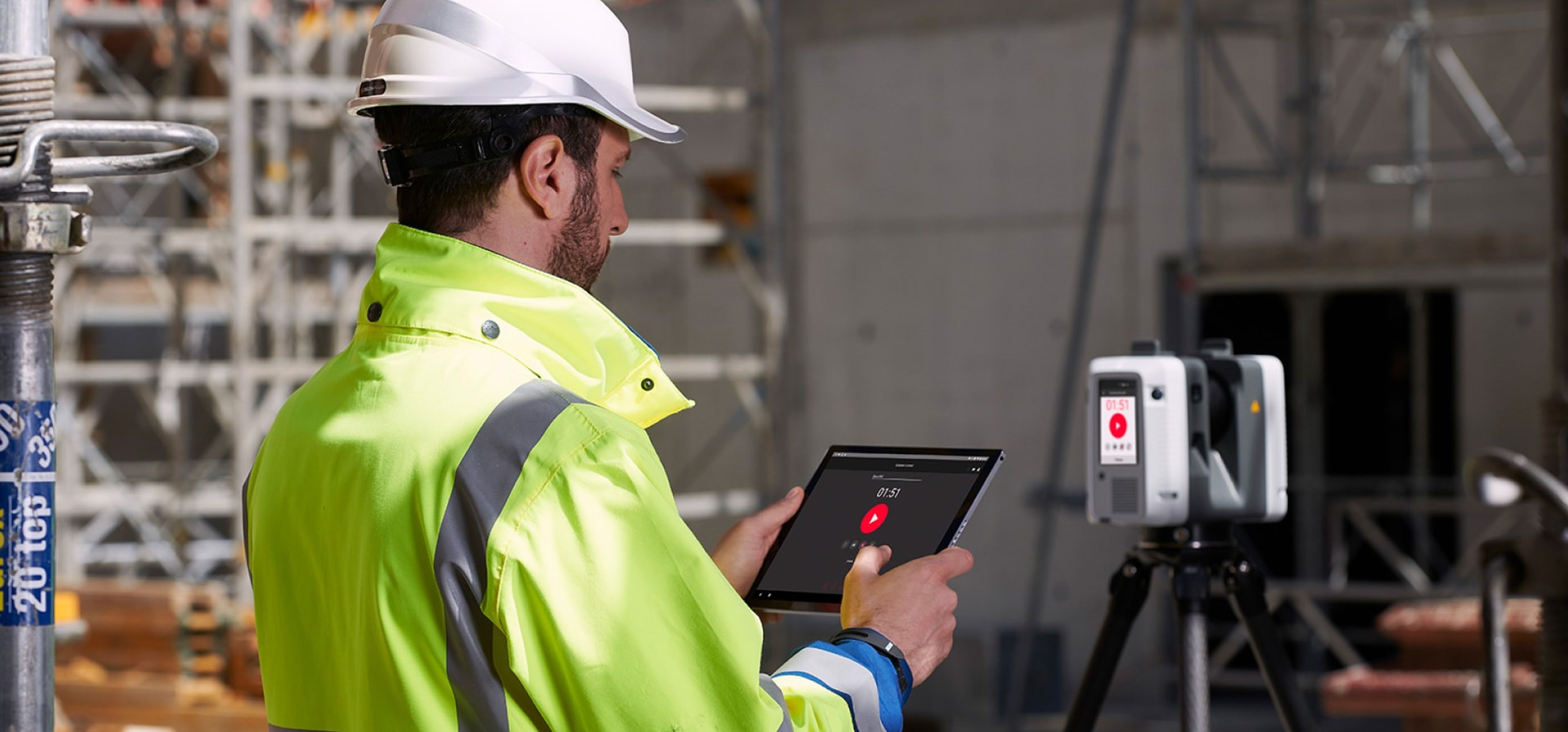 Mann auf der Baustelle bedient das Tablet mit Cyclone FIELD 360-App von Leica Geosystems.