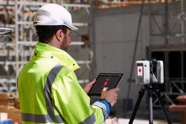 Mann auf der Baustelle bedient das Tablet mit Cyclone FIELD 360-App von Leica Geosystems.