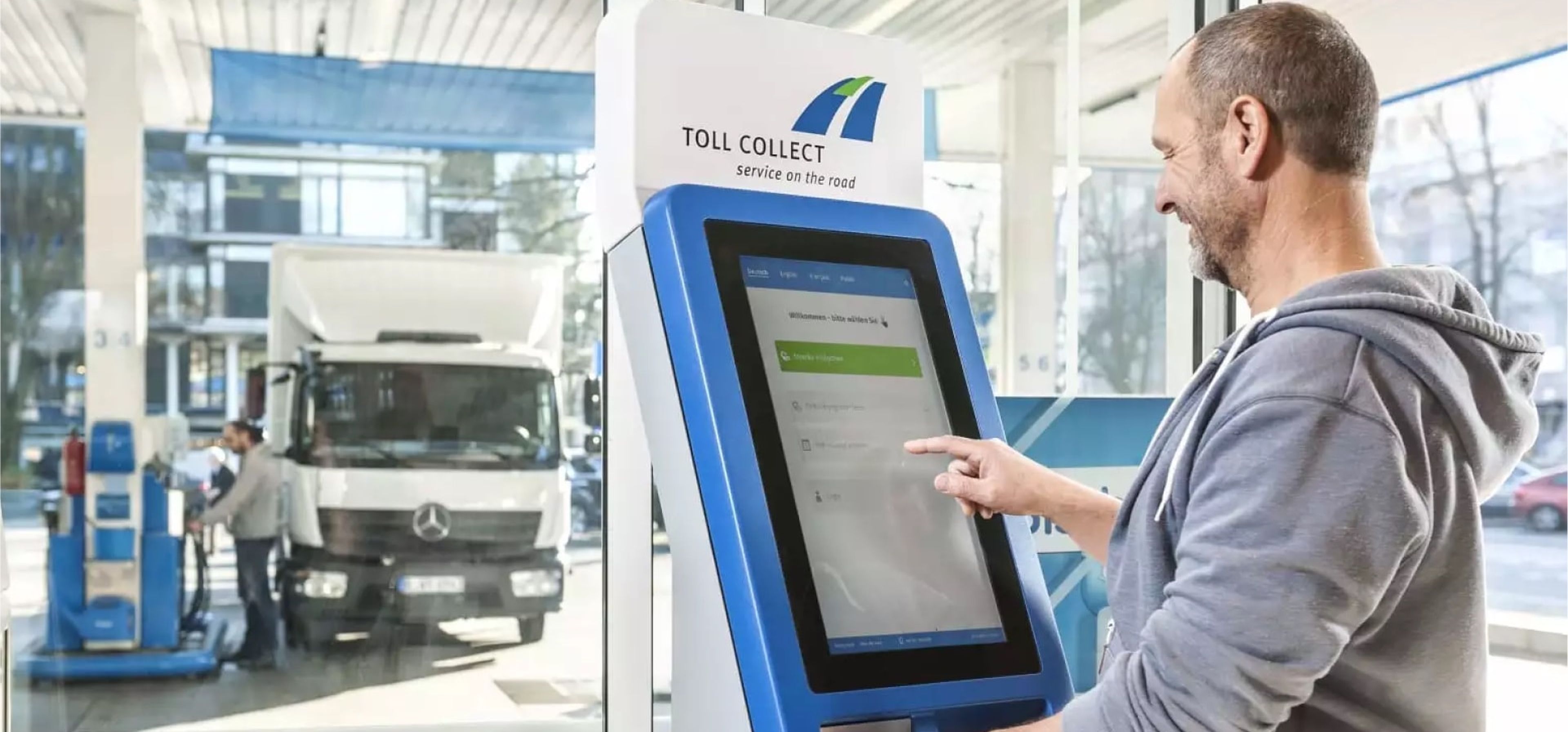 LKW Fahrer bedient Toll Collect Terminal an einer Tankstelle.