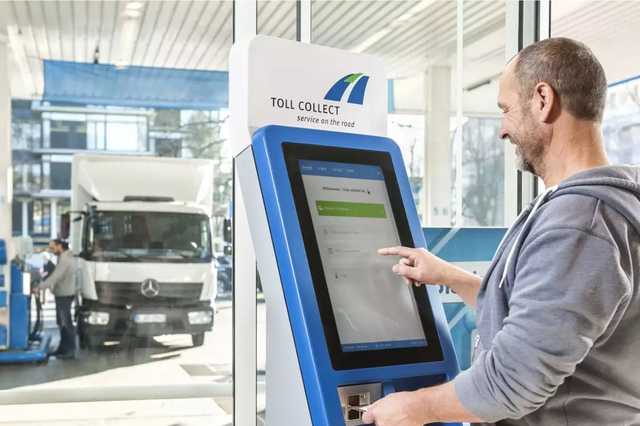 LKW Fahrer bedient Toll Collect Terminal an einer Tankstelle.